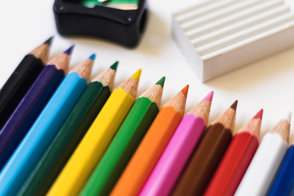 a row of colored pencils next to a sharpener