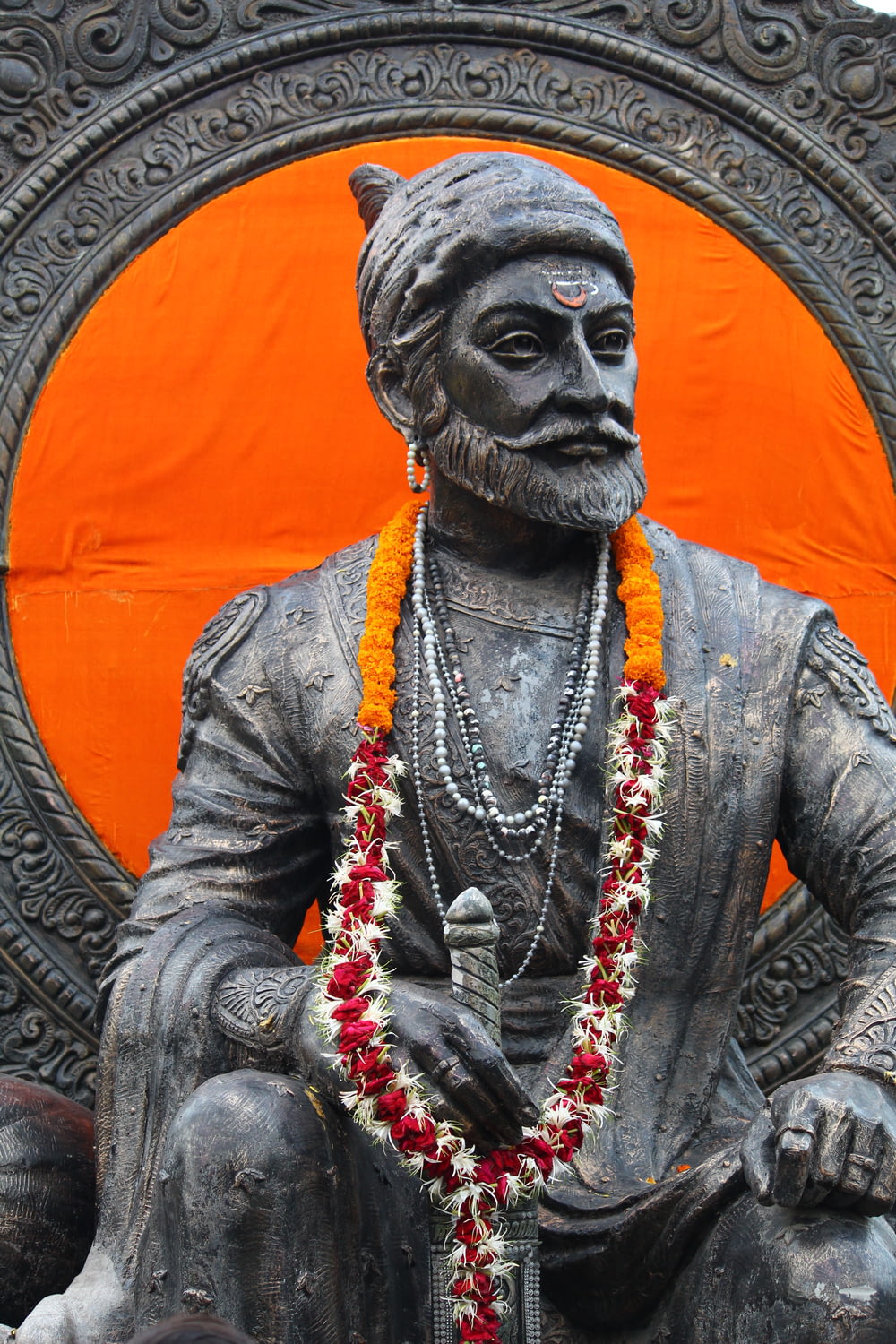 a statue of a man sitting in front of an orange circle