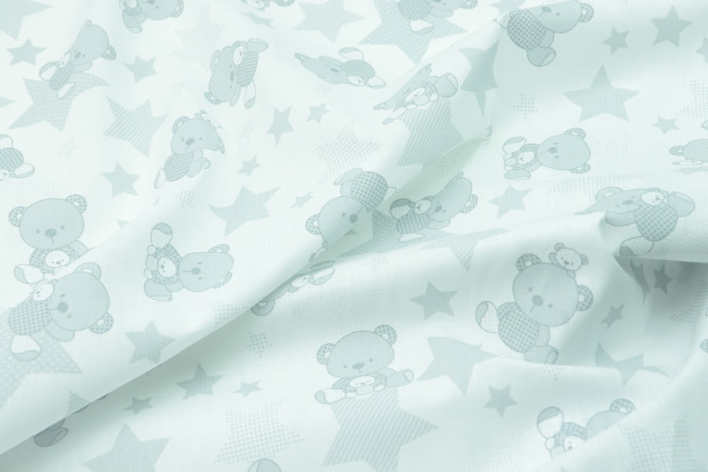 a close up of a white fabric with teddy bears on it