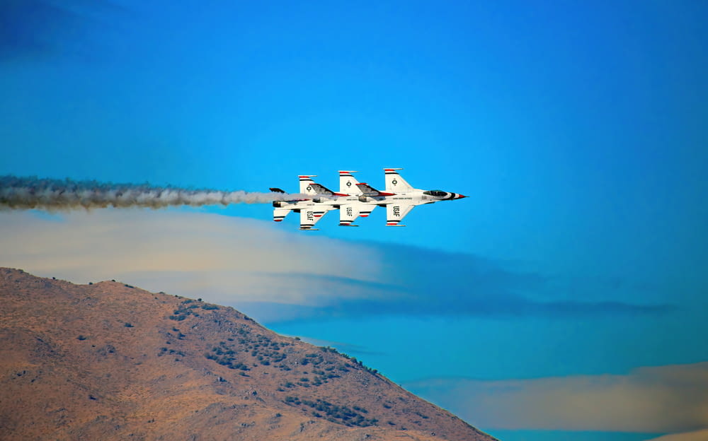 two jets flying in the sky near a mountain