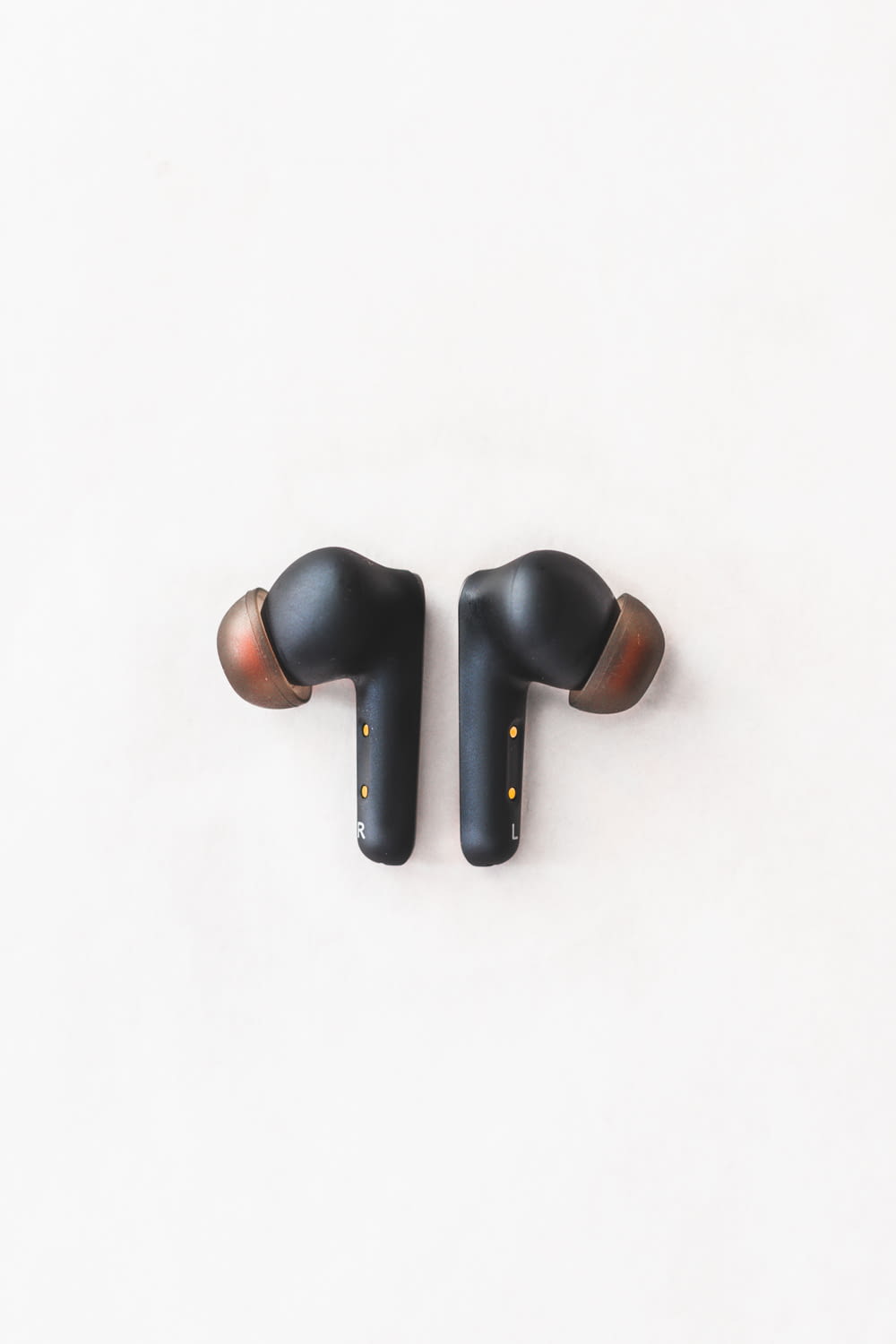 a pair of black ear buds sitting on top of a white surface