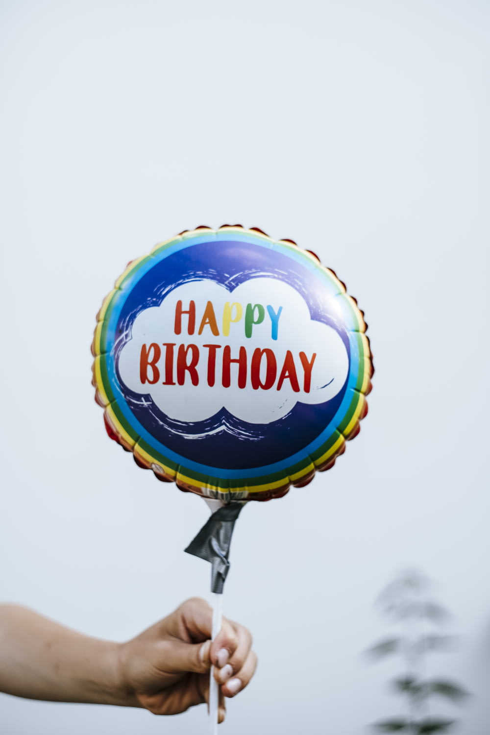 Eine Person, die einen Ballon hält, auf dem alles Gute zum Geburtstag steht