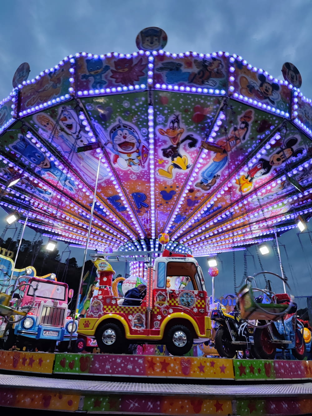 a brightly lit carnival ride with a colorful car