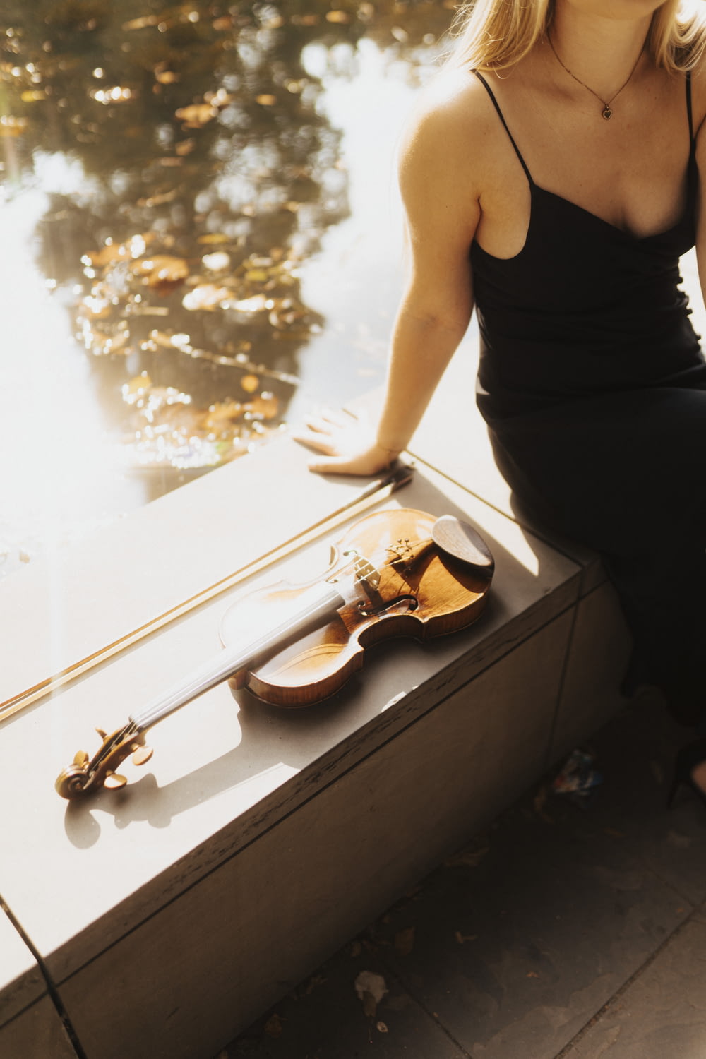 a woman sitting on a ledge next to a violin