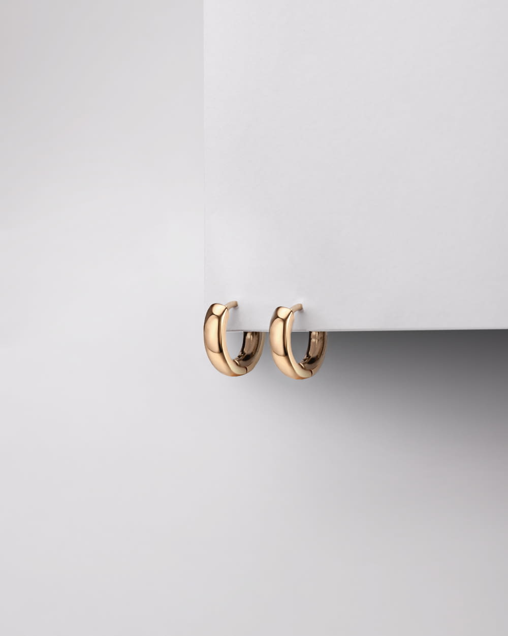a pair of gold hoop earrings on a white surface