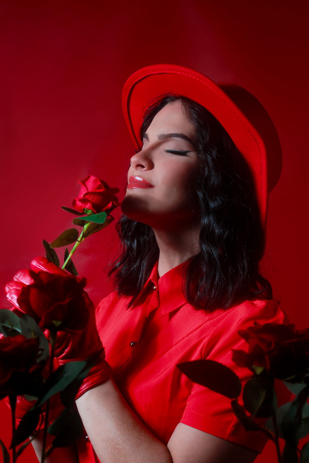 a woman wearing a red hat and holding a rose