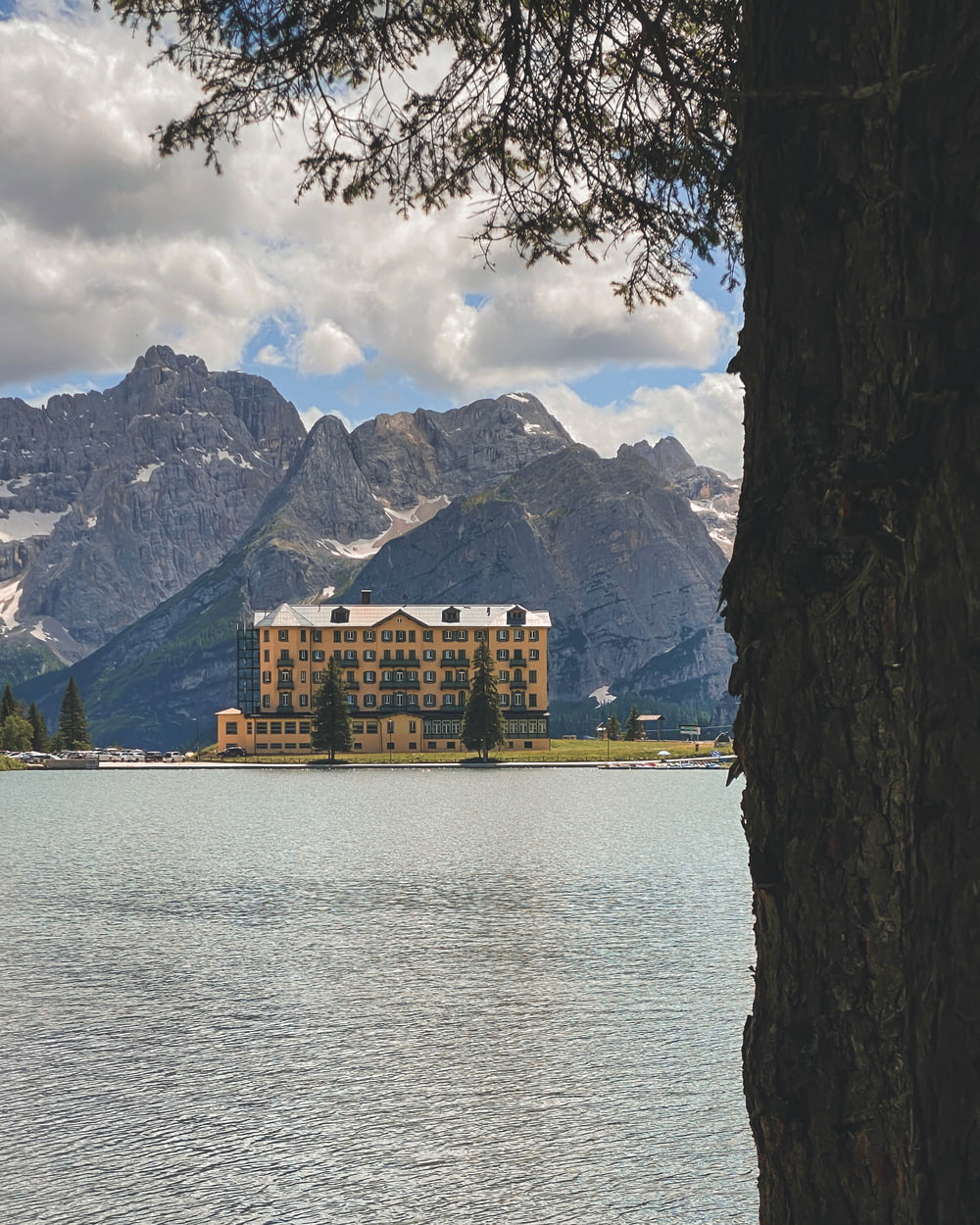 a large building sitting on top of a lake surrounded by mountains