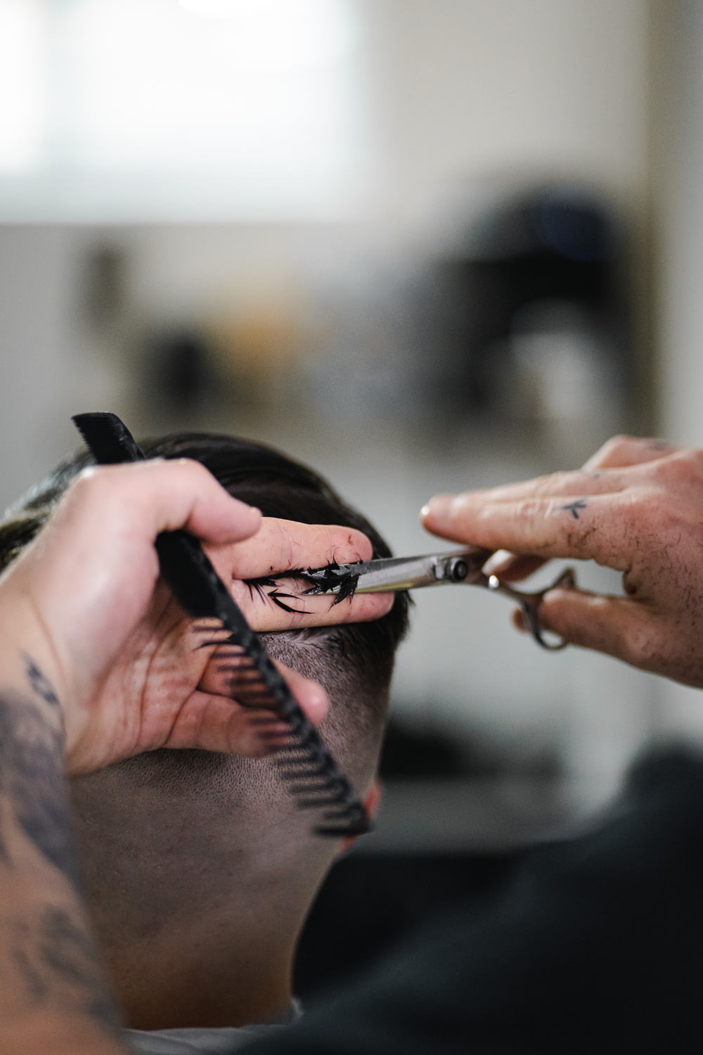 a person cutting another persons hair with scissors