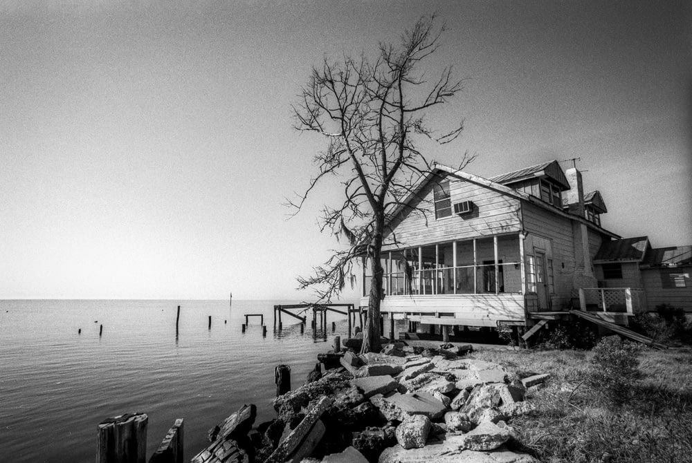 Une photo en noir et blanc d’une maison au bord de l’eau
