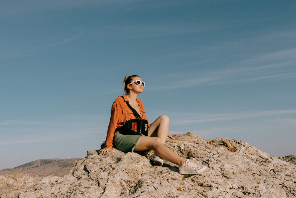 Una donna seduta sulla cima di una grande roccia