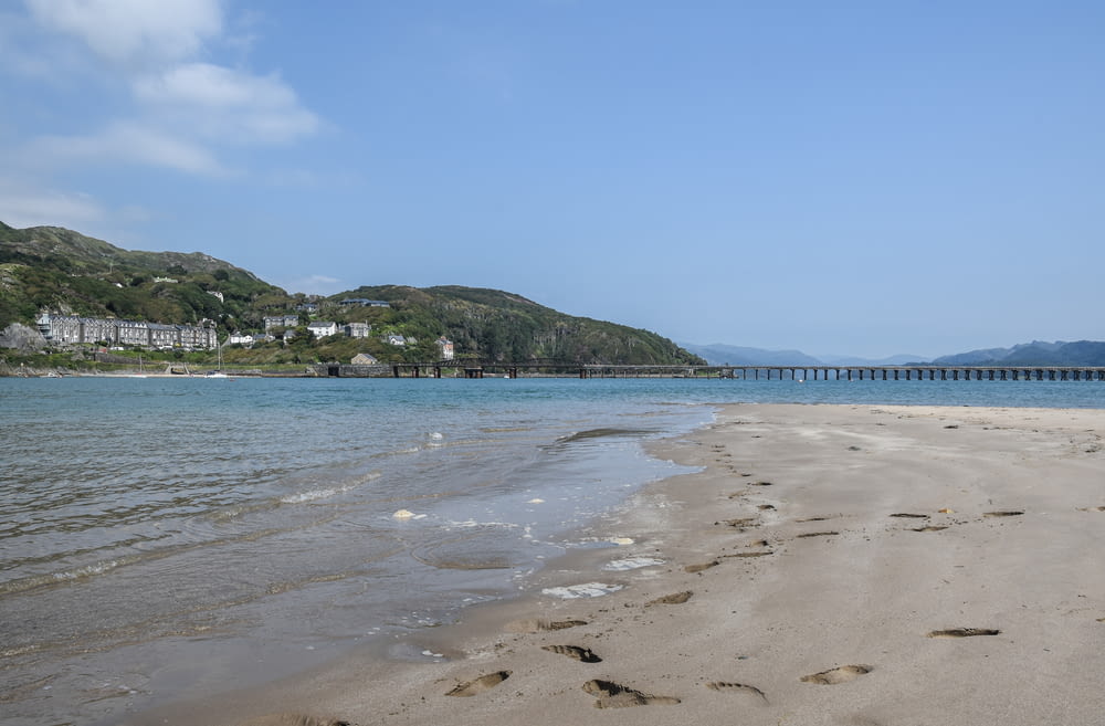 a sandy beach with a bridge in the background