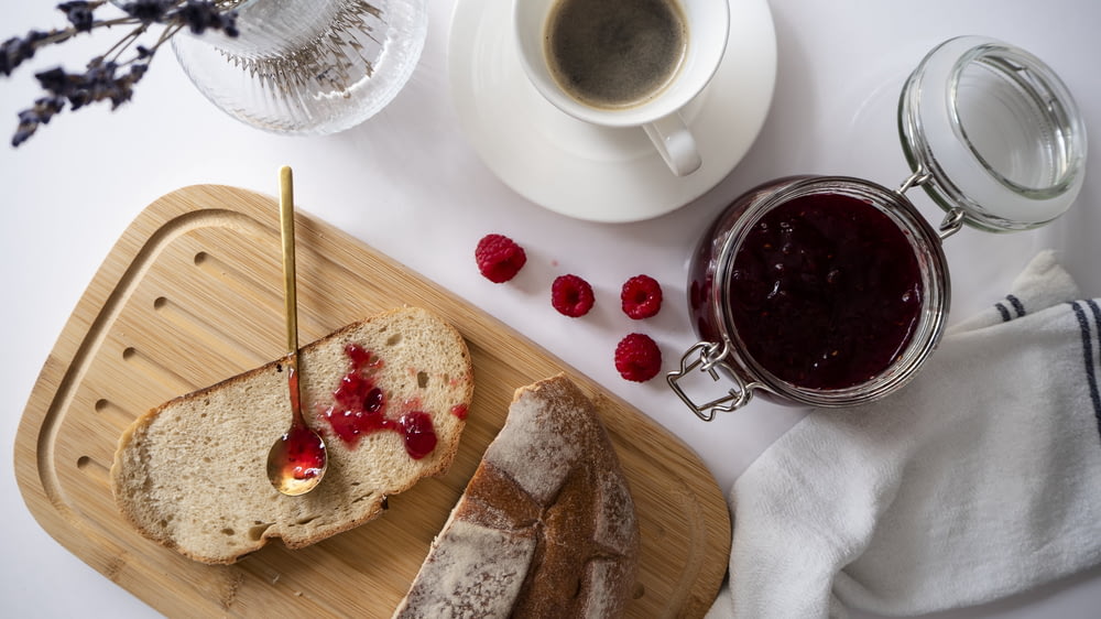 a loaf of bread with raspberry jam and a cup of coffee
