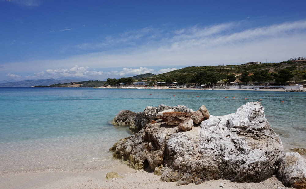 a beach with clear blue water and rocks