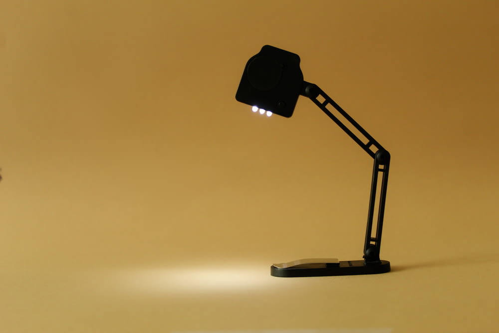 a black desk lamp on a yellow background
