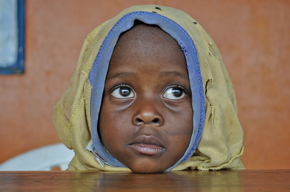a young child wearing a yellow and blue head covering
