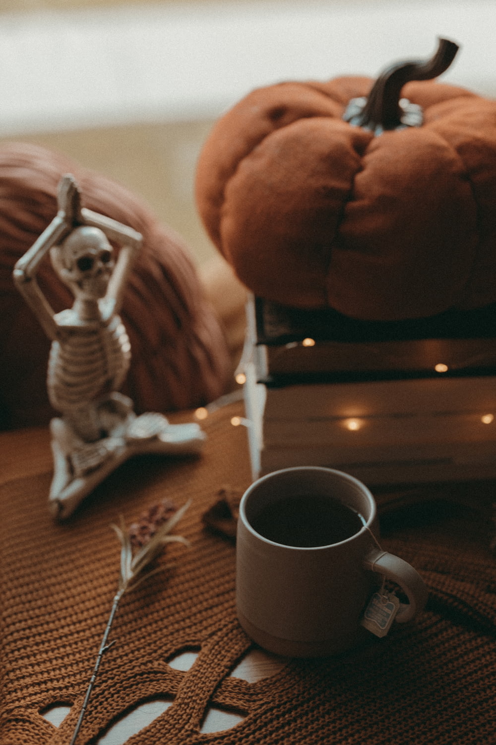 a skeleton figurine sitting on top of a table next to a cup of