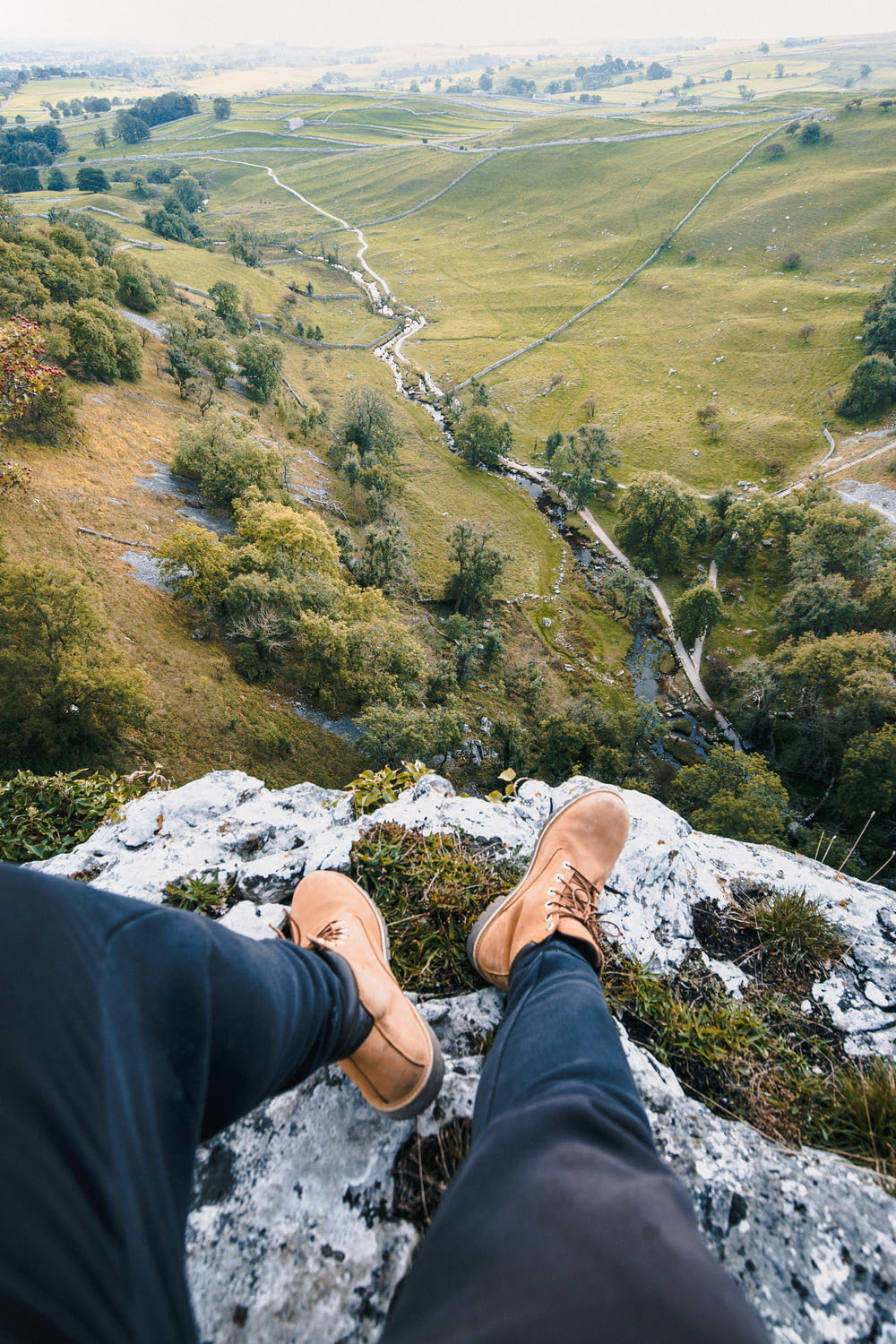 una persona seduta su una roccia che domina una valle