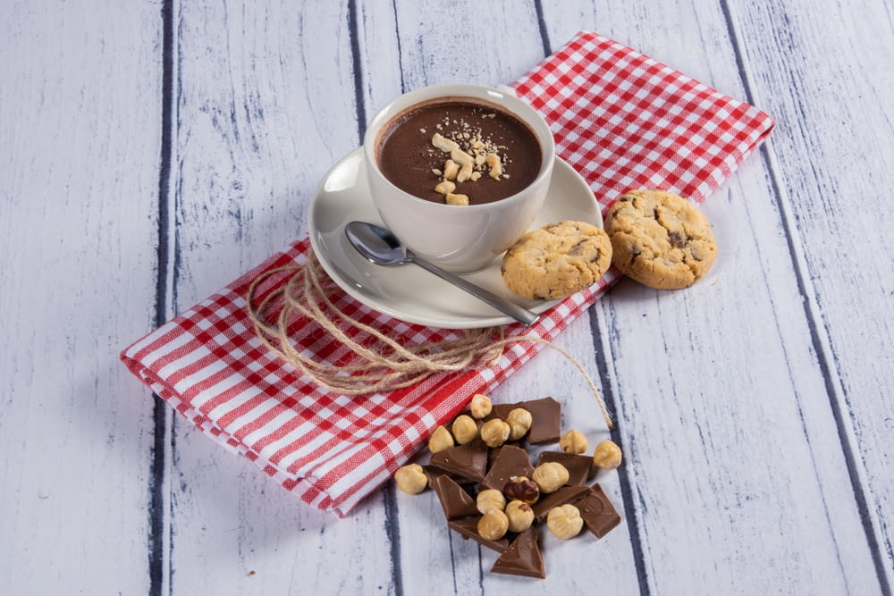 a cup of hot chocolate and cookies on a red and white checkered napkin