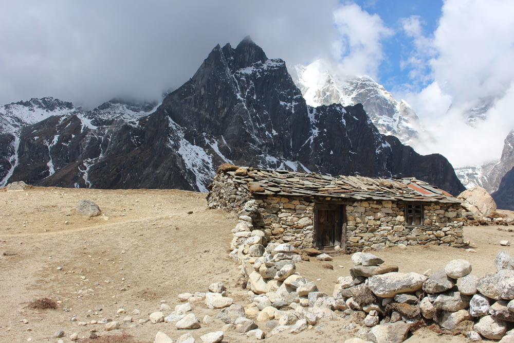a stone hut with a mountain in the background