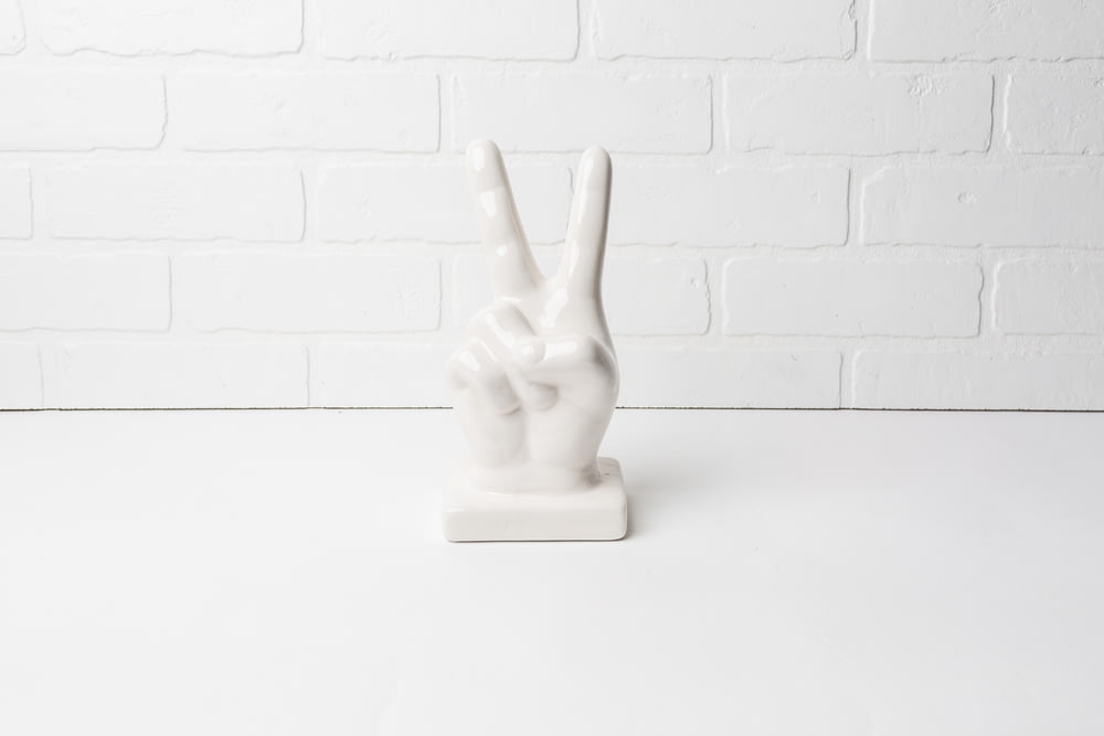 a white statue of a peace sign on a white table