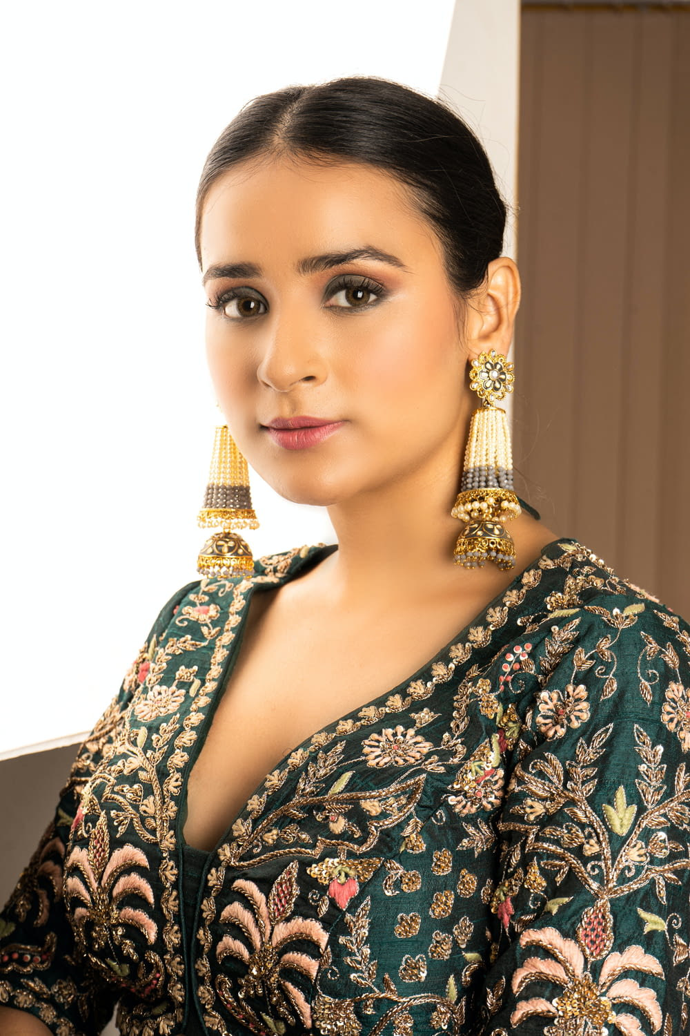 a woman in a green dress with gold earrings