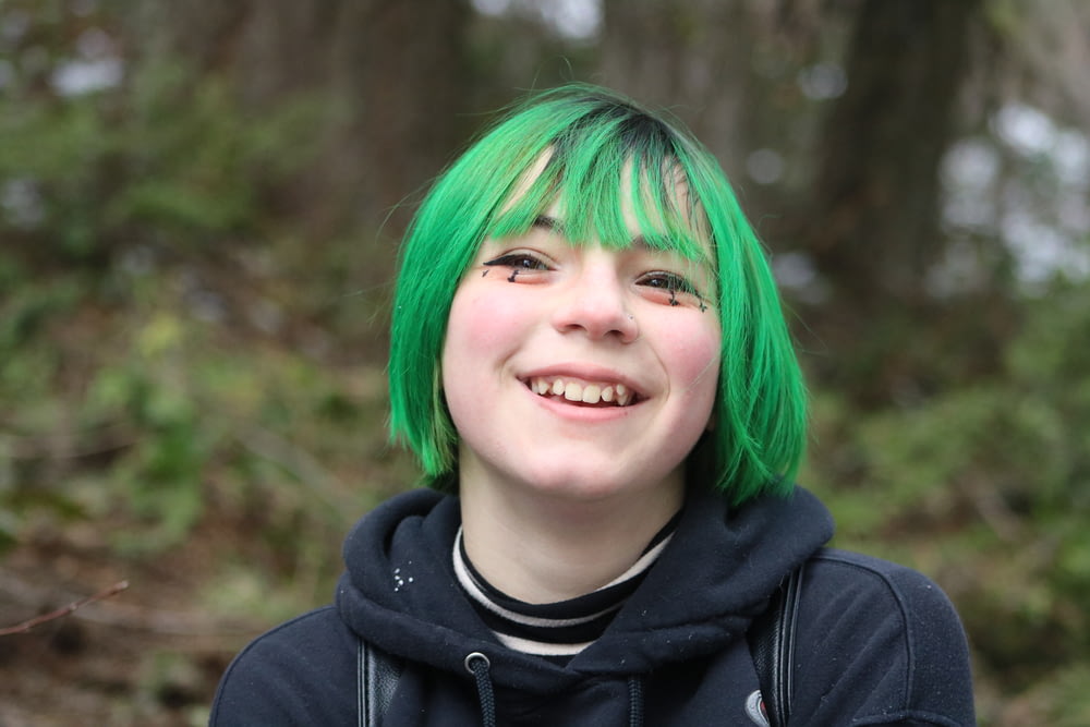 a girl with green hair and a black hoodie