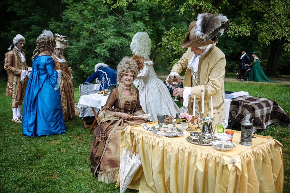 a group of people dressed in period costumes at a tea party