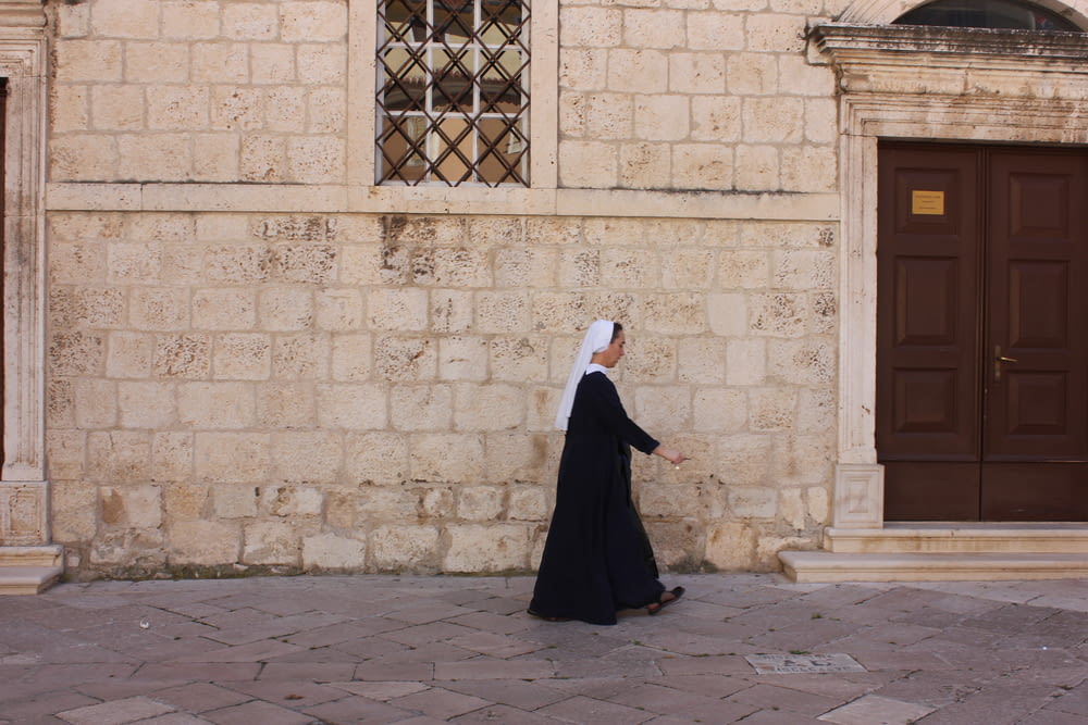 a woman in a white veil walking past a building