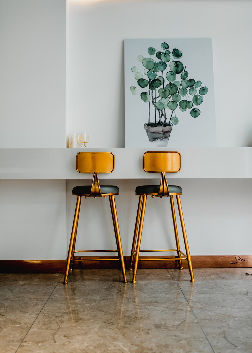 two yellow stools in front of a painting on a wall