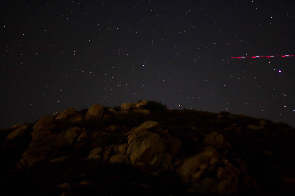 a plane flying over a rocky hillside at night