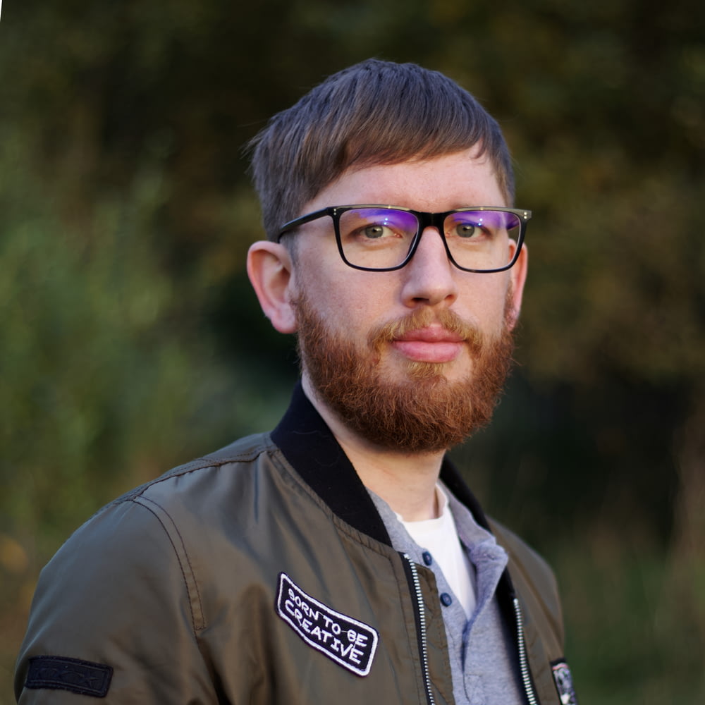 a man with a beard wearing glasses and a jacket