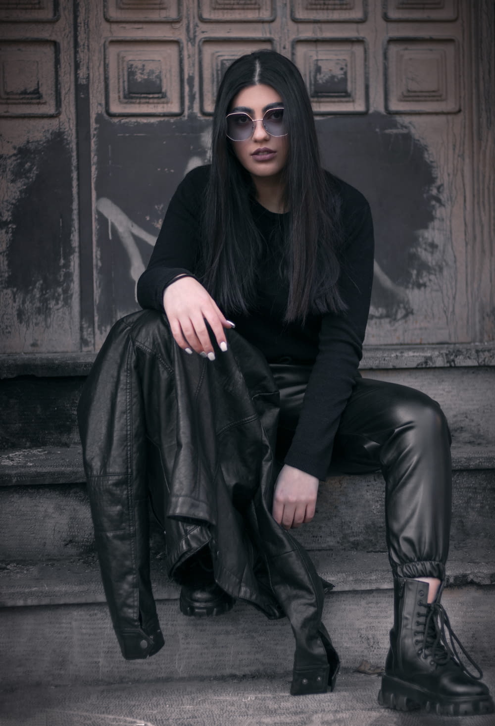 a woman sitting on a step wearing black leather pants