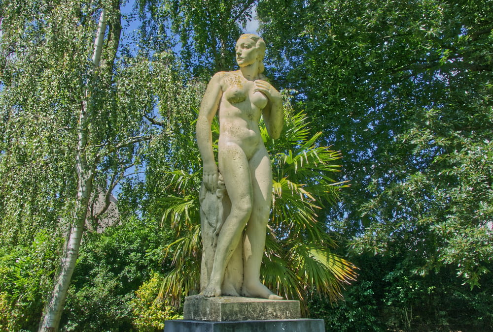 a statue of a naked woman in a park