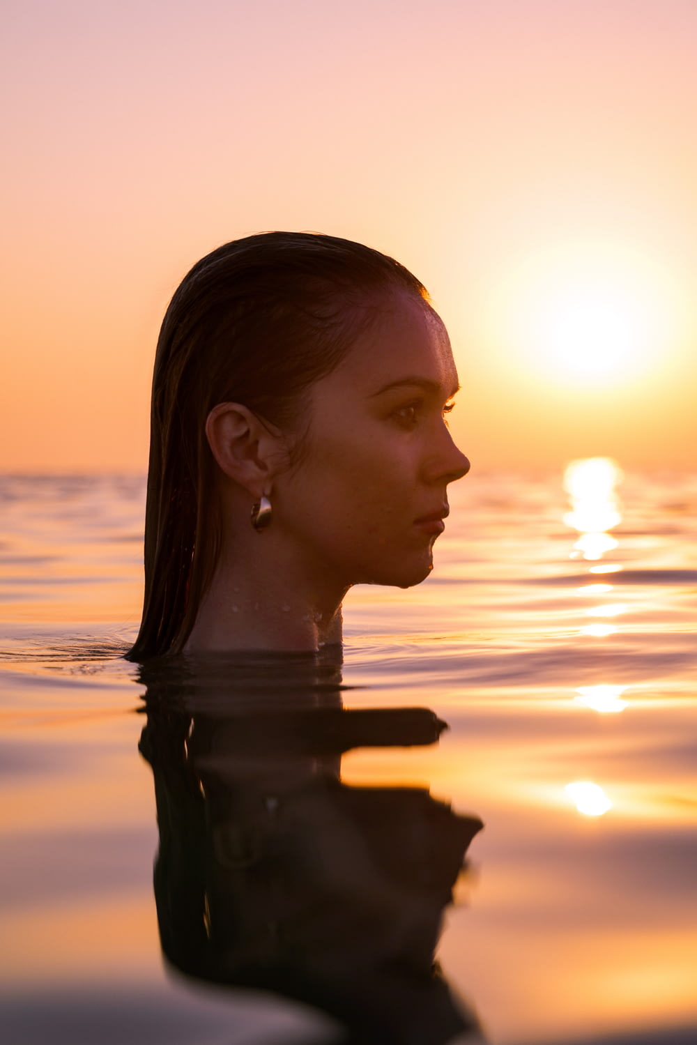 a woman standing in the water at sunset