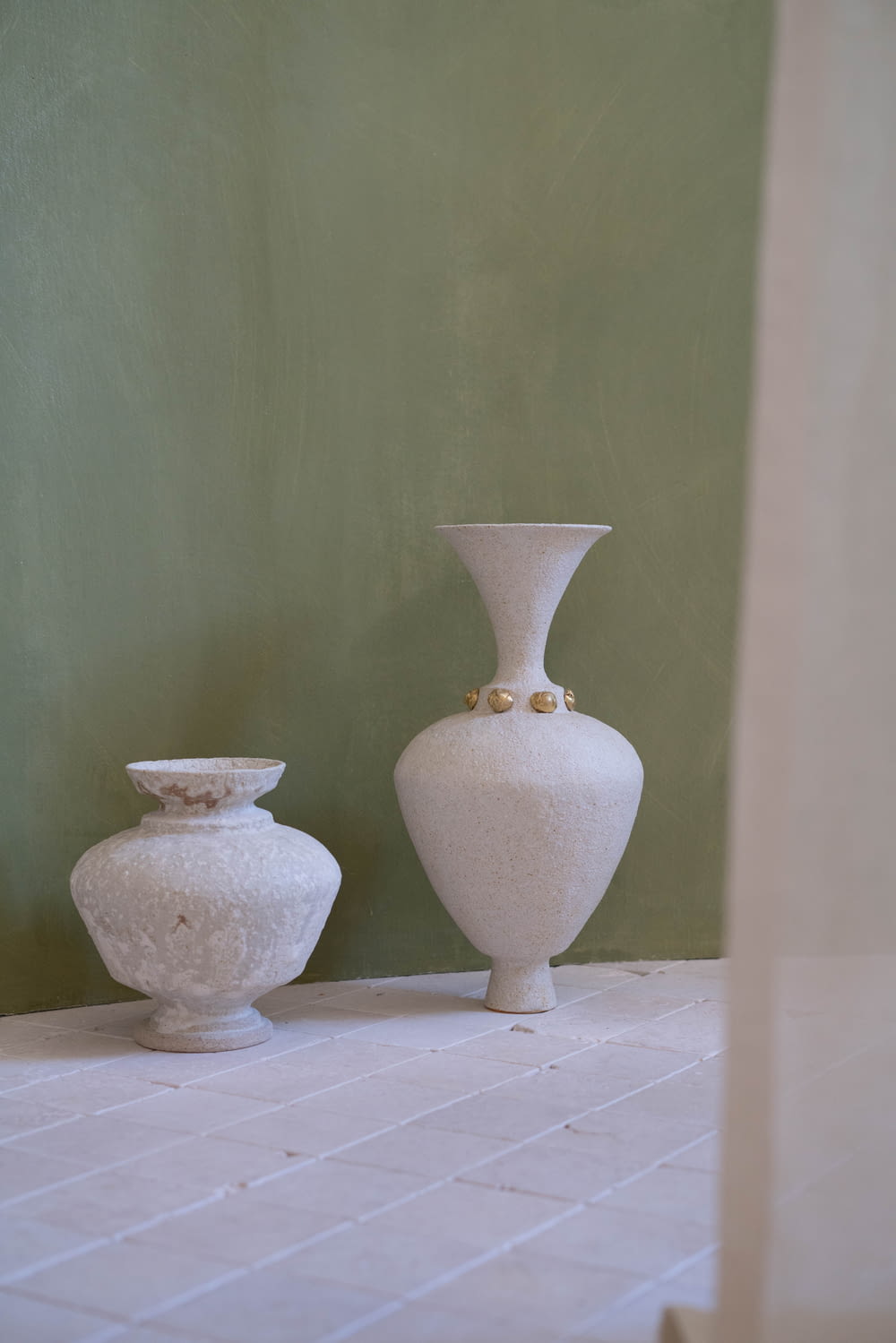 a couple of white vases sitting on top of a tiled floor