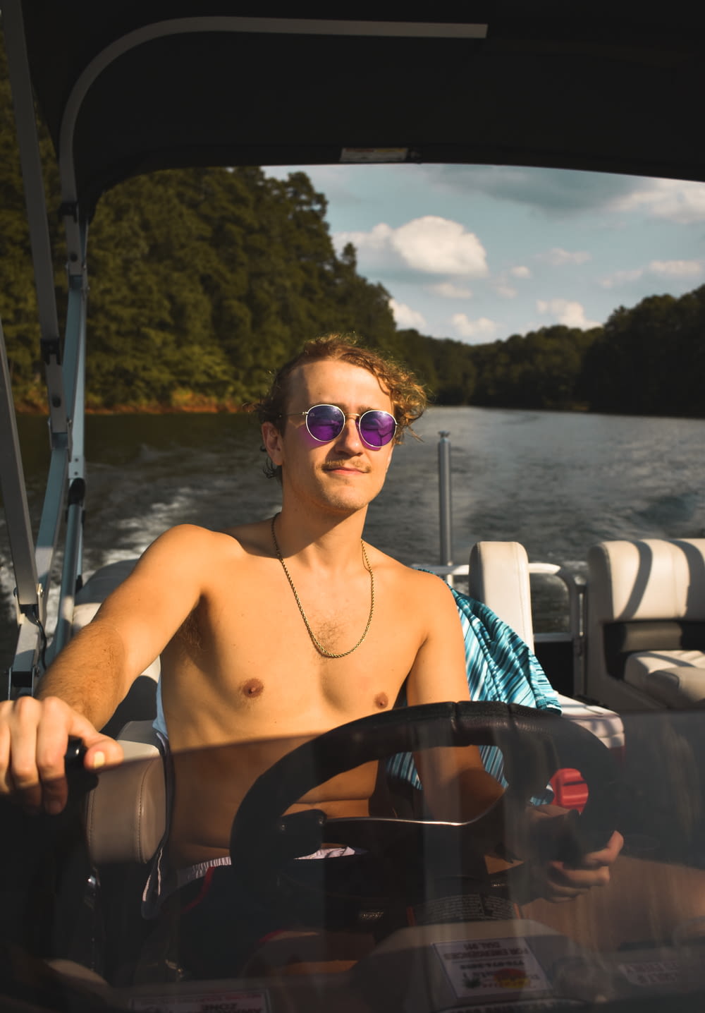 a shirtless man driving a boat on a lake