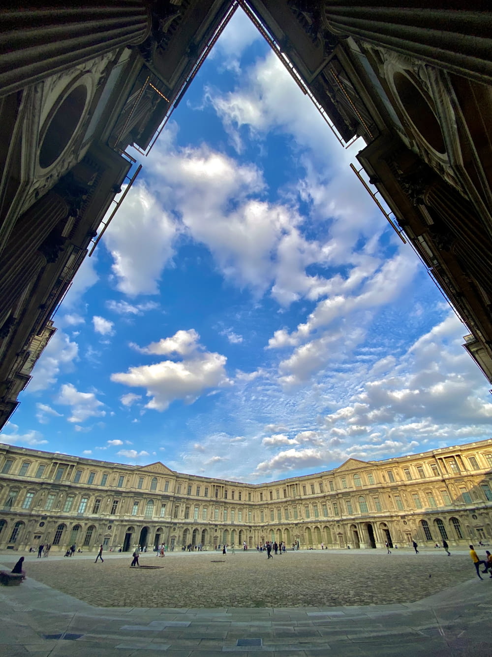 a large building with a sky filled with clouds
