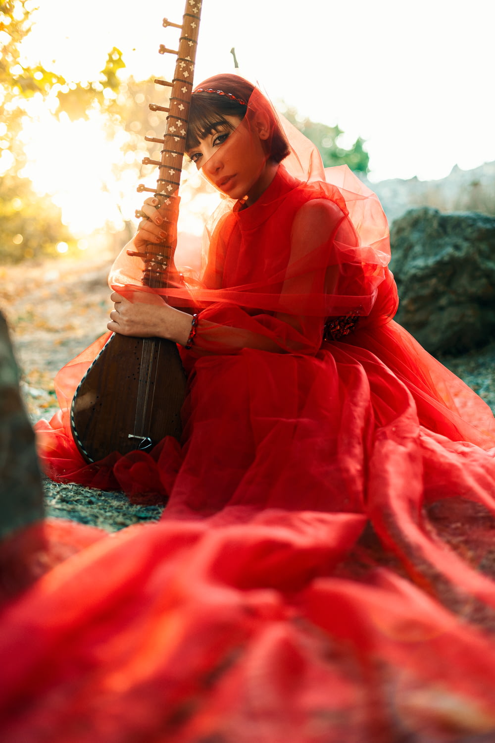 Une femme en robe rouge tient une guitare