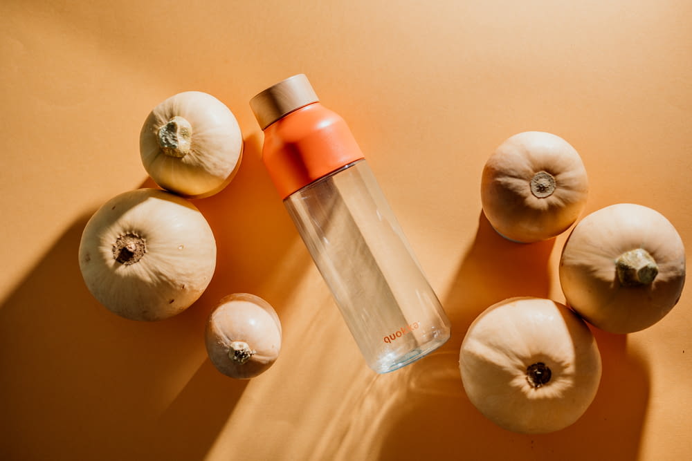 a bottle of water surrounded by onions and garlic