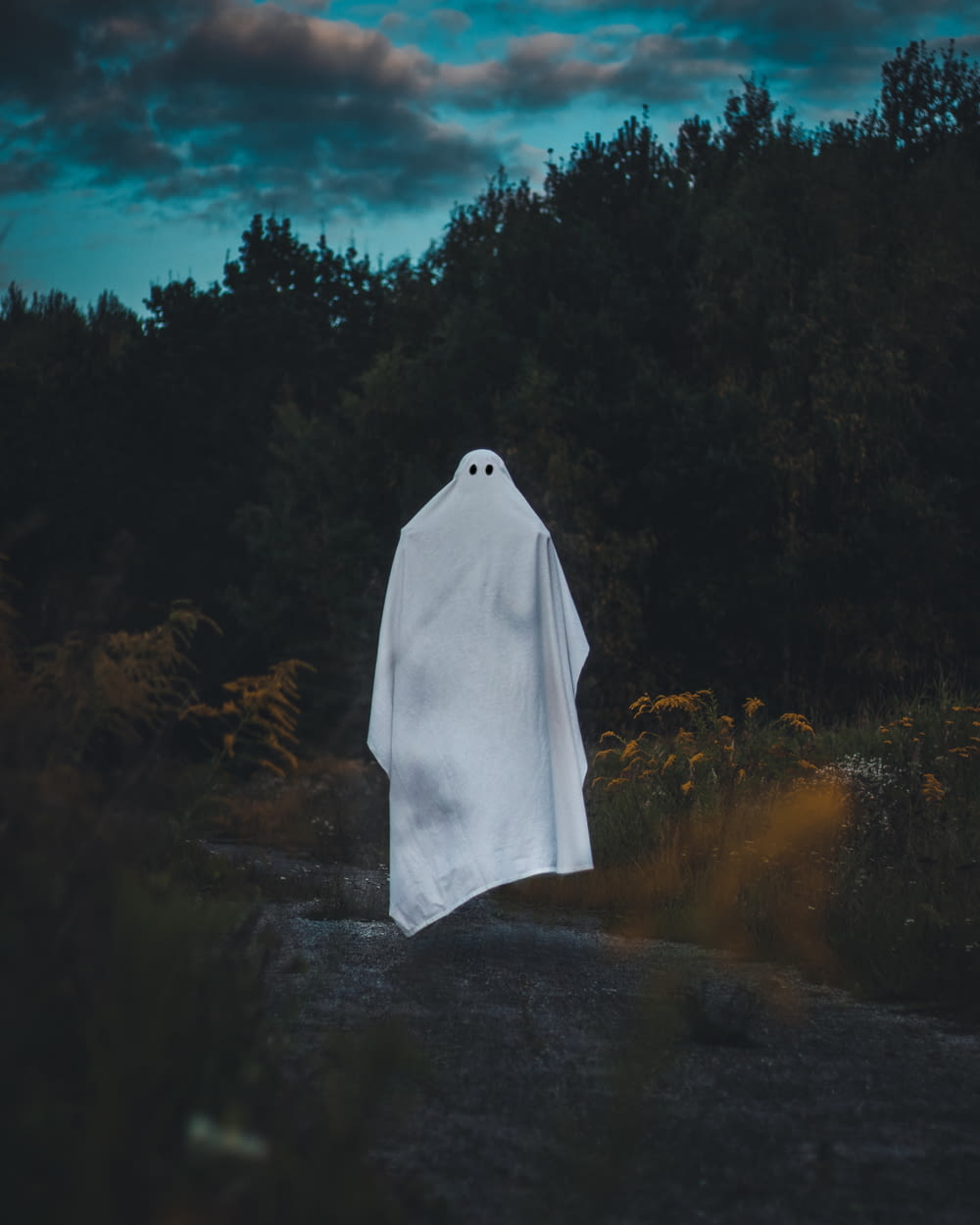 a white ghost standing in the middle of a forest