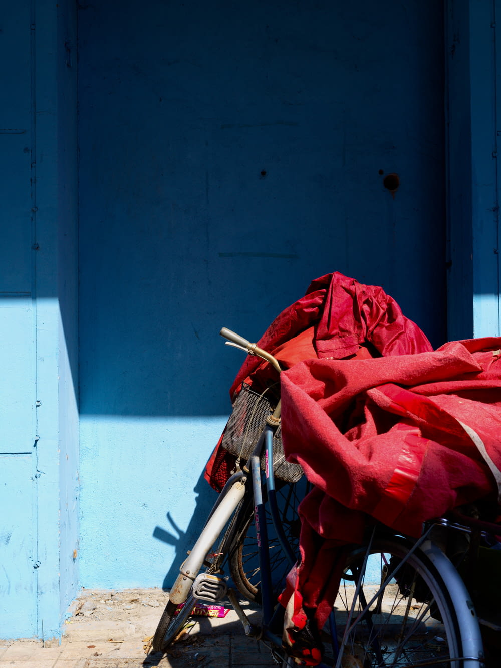 青い建物の前に赤い毛布をかぶった自転車が停まっている