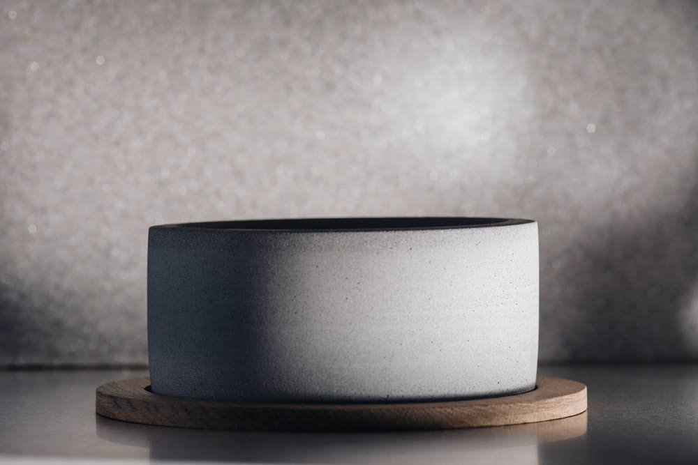 a gray and white bowl sitting on top of a wooden stand