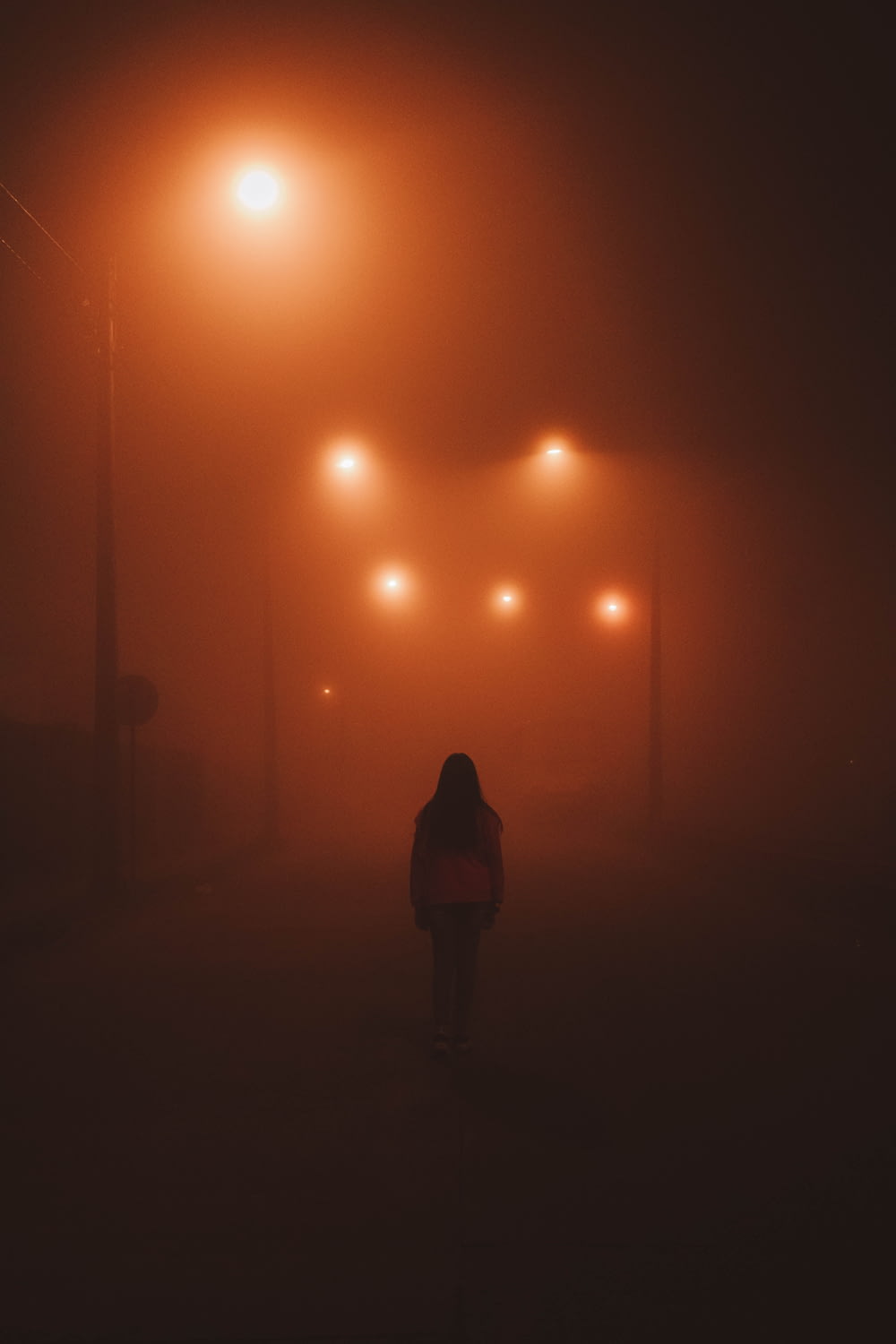 a person walking down a street at night in the fog