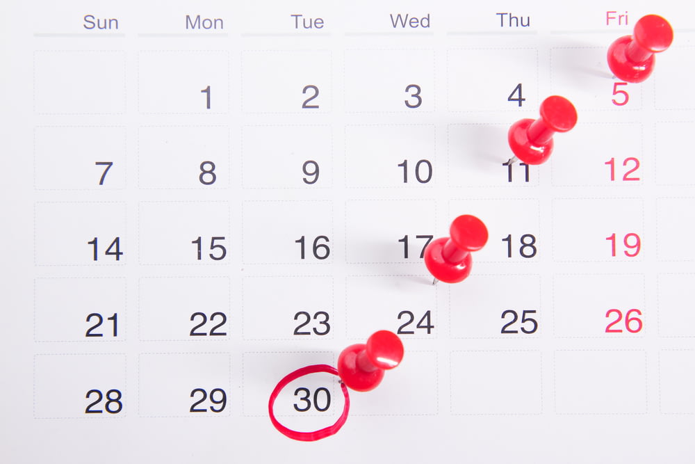 un calendrier avec des boutons-poussoirs rouges épinglés