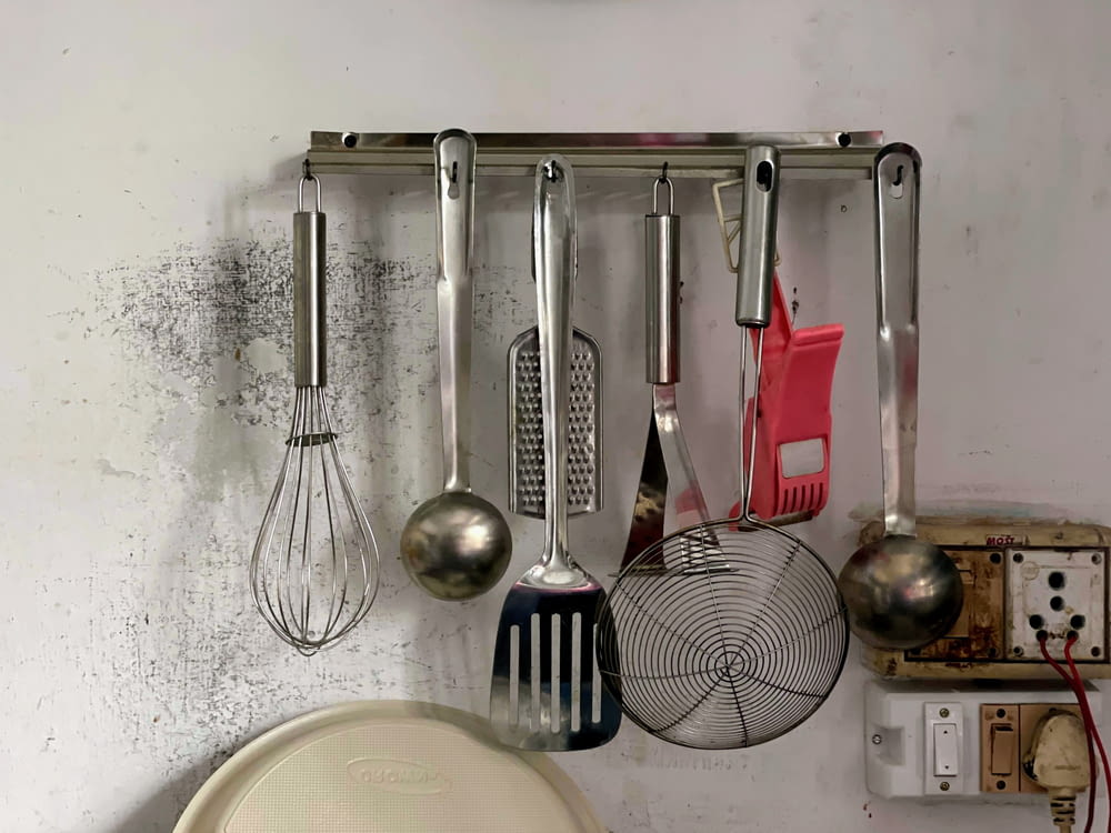 a kitchen wall with a bunch of cooking utensils hanging on it