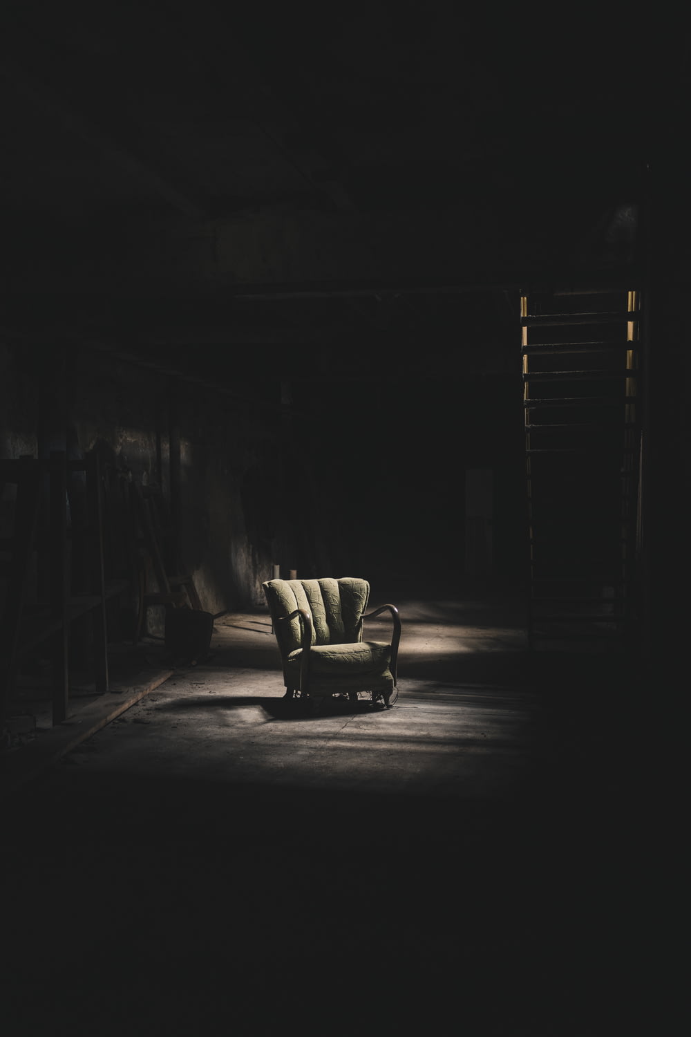 um quarto escuro com uma cadeira e uma escada