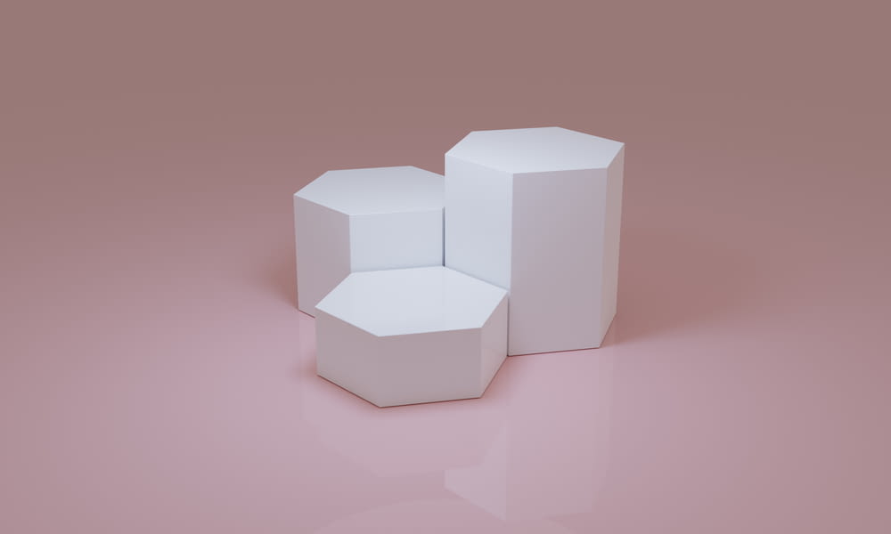 three white boxes sitting on top of a pink surface