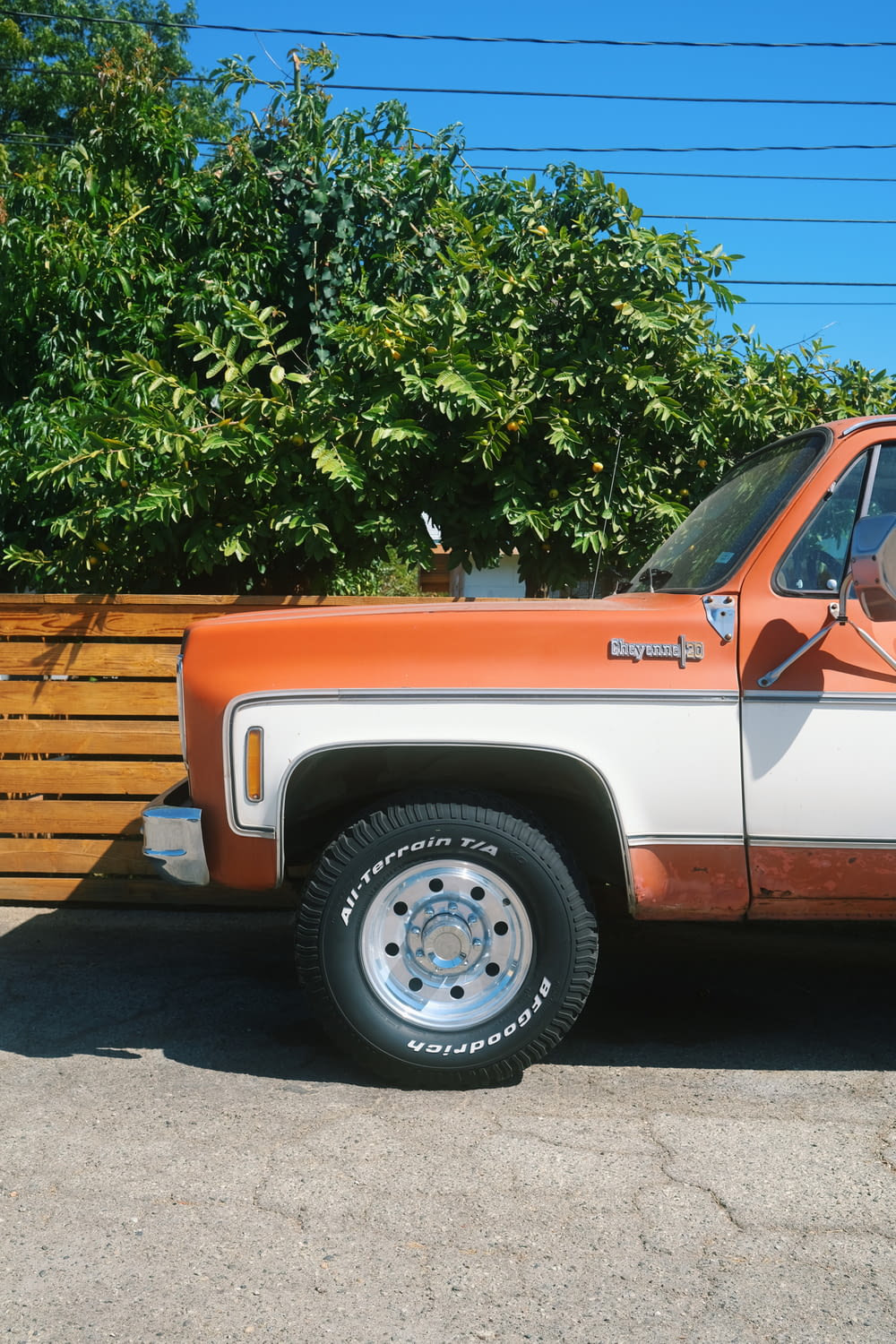 an orange and white truck parked next to a wooden fence