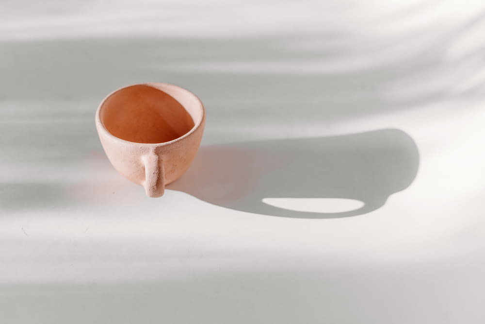 a brown cup sitting on top of a white table