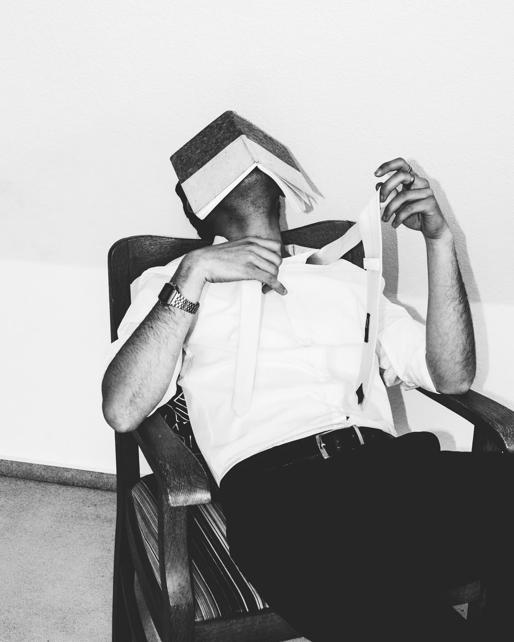 a man sitting in a chair with a paper hat on his head